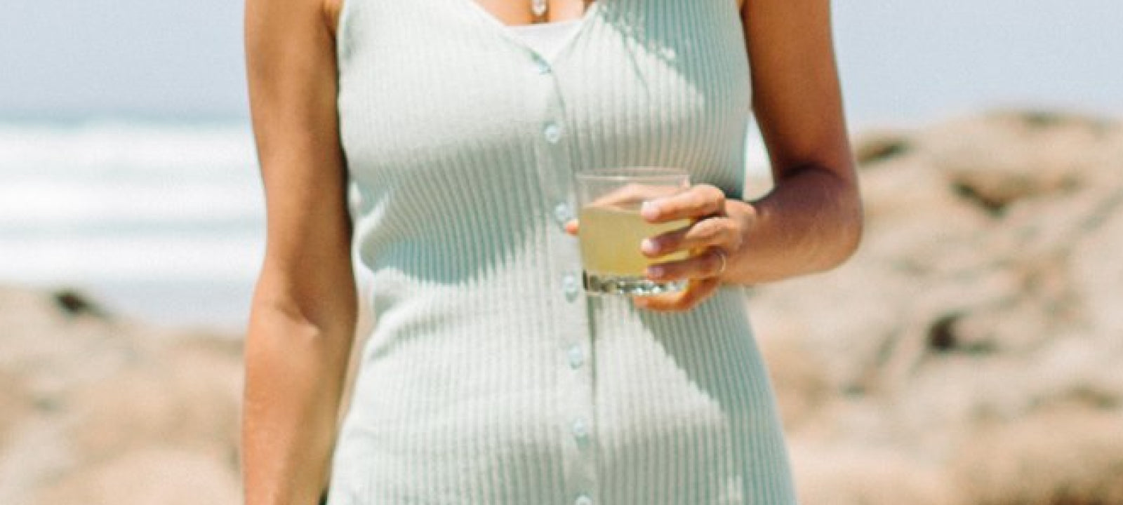Frau am Strand genießt ein Your Super-Getränk