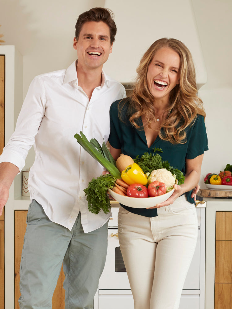 Kristel und Michael lachen, während sie einen großen Teller mit Gemüse in der Hand halten